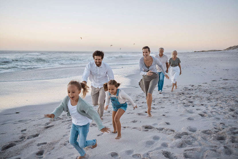 Großfamilie rennt lachend bei Sonnenuntergang am Strand